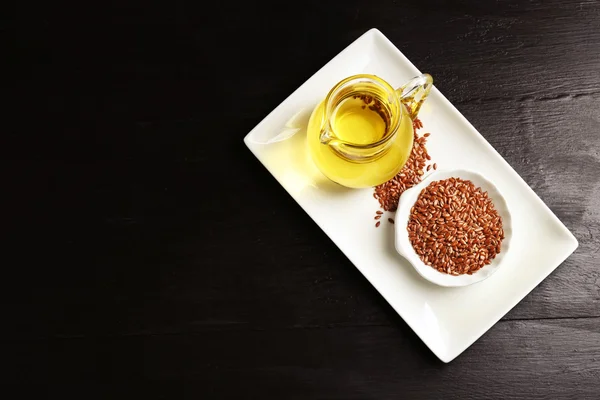 Semillas de lino con aceite sobre mesa de madera —  Fotos de Stock