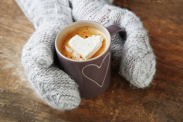 Femme mains dans les mitaines tenant une tasse de café — Photo