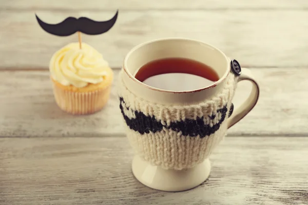 Delicioso magdalena creativa con bigote y taza de té en la mesa de madera — Foto de Stock