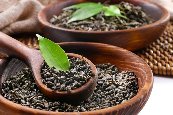 Té seco con hojas verdes en utensilio de madera, de cerca —  Fotos de Stock