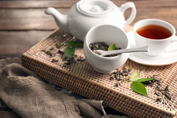 Té granulado con hojas verdes en juego de té en bandeja de mimbre primer plano —  Fotos de Stock