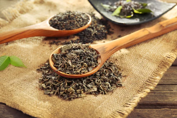 Granulated tea with green leaves on sackcloth closeup — Stock Photo, Image