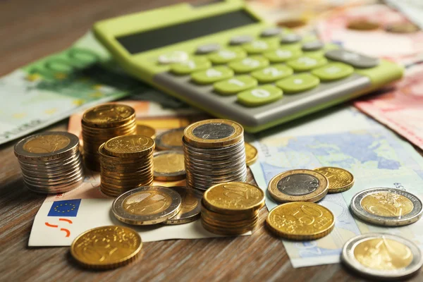 Concepto de dinero. Calculadora verde con billetes y monedas sobre mesa de madera —  Fotos de Stock