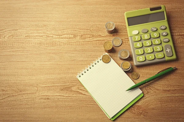 Geld concept. Groene calculator met munten en notitieblok op houten tafel — Stockfoto