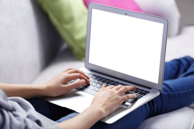 Kanepede dizüstü bilgisayarlı bir kadın oturuyor. 