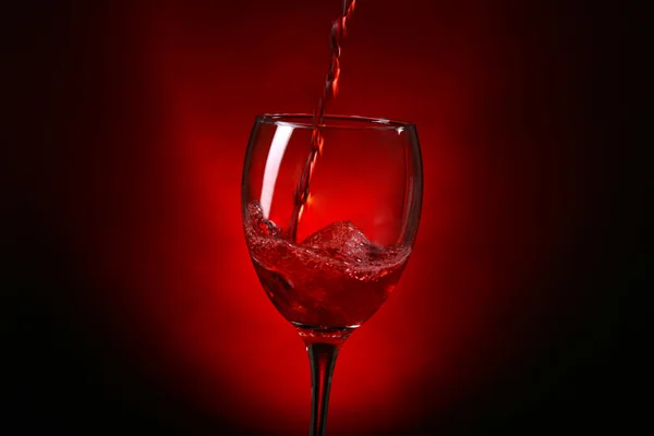 Wine pouring in glass on dark red background — Stock Photo, Image