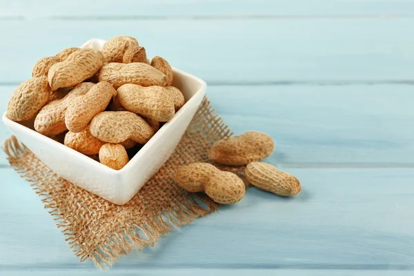 Peanuts in the bowl on blue wooden background — Stock Photo, Image