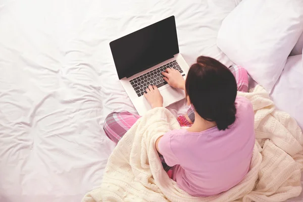 Kvinna i pyjamas med laptop — Stockfoto