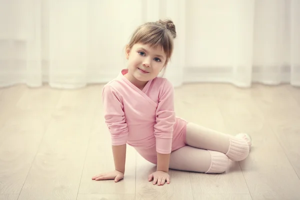 Το μικρό χαριτωμένο κορίτσι στο ροζ κορμάκι που κάθεται στο πάτωμα στο στούντιο χορού — Φωτογραφία Αρχείου