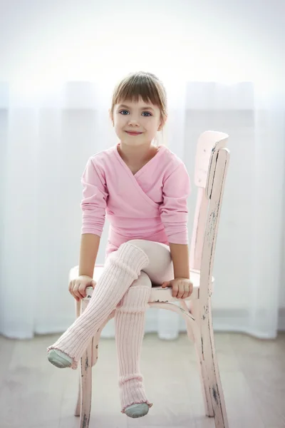 可爱的小女孩在粉红色紧身连衣裤，坐在椅子上在舞蹈工作室 — 图库照片