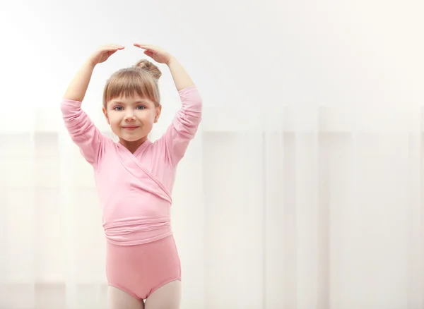 Маленькая симпатичная девочка в розовом трико делает новое балетное движение в танцевальной студии — стоковое фото