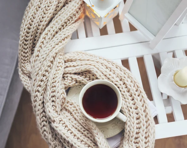 Tasse Tee und Strickschal auf Couchtisch im Zimmer, Nahaufnahme — Stockfoto