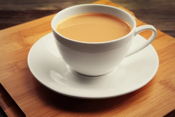 Porcelanowa filiżanka herbaty z mlekiem na drewnianej tacy, z bliska — Zdjęcie stockowe