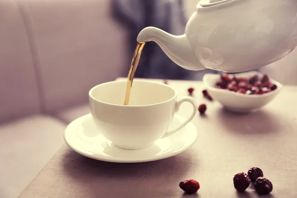 Gieten van rose hip thee in beker, huis sfeer — Stockfoto