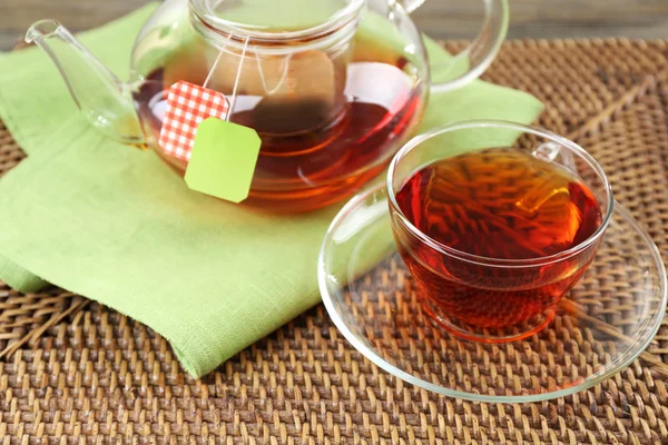 Xícara de chá com sacos de chá e bule de chá sobre fundo de mesa de madeira — Fotografia de Stock