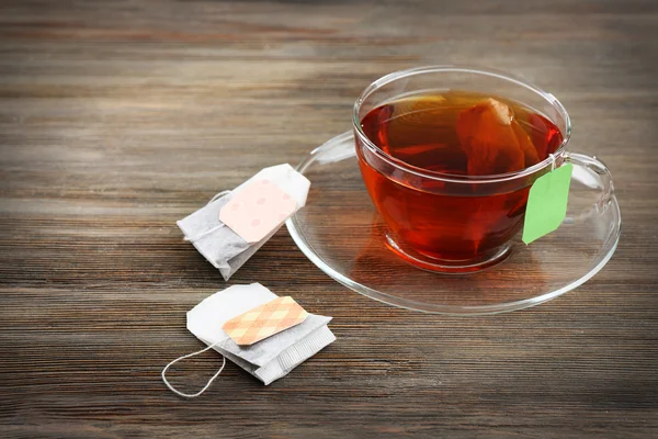 Xícara de chá com sacos de chá no fundo da mesa de madeira — Fotografia de Stock