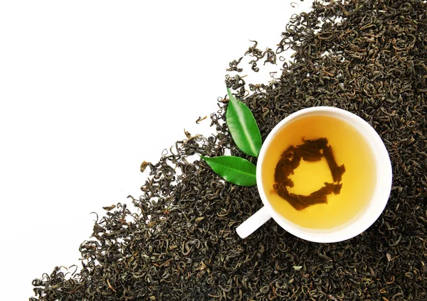 Tasse mit aufgebrühtem, trockenem Tee und grünen Blättern, isoliert auf weißem — Stockfoto