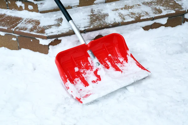 Red shovel for snow removal beside stairs — Stock Photo, Image