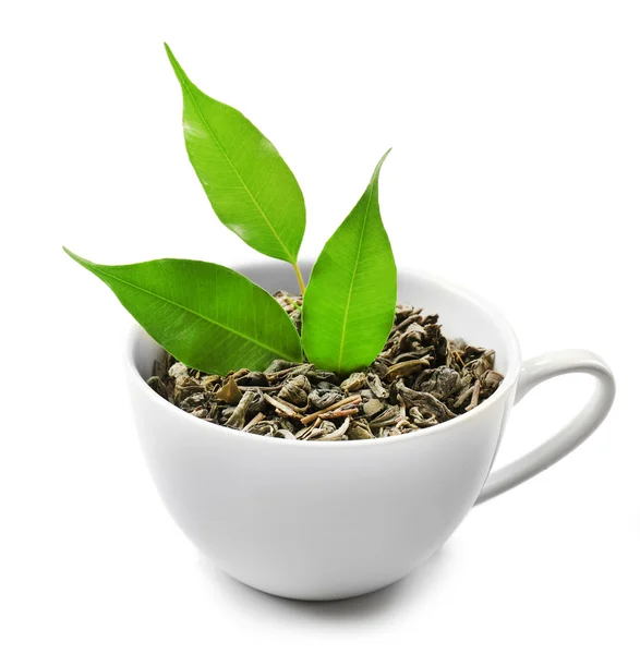 Cup with dry tea and green leaves, isolated on white — Stock Photo, Image