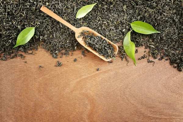 Scattered tea with green leaves on wooden table background, copy space — Stock Photo, Image