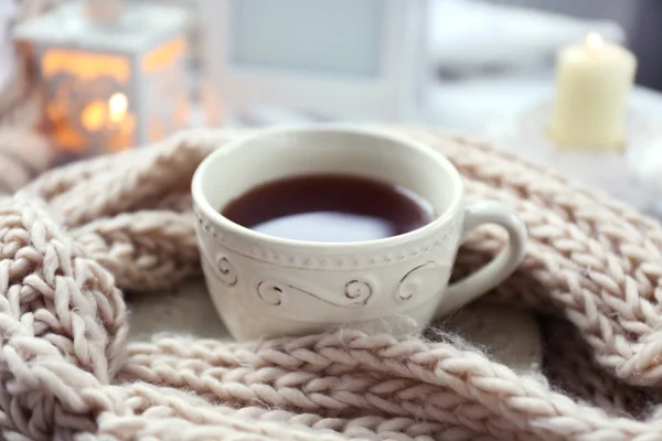 Cup of tea and knitted scarf on coffee table in the room, close up — Stock Photo, Image