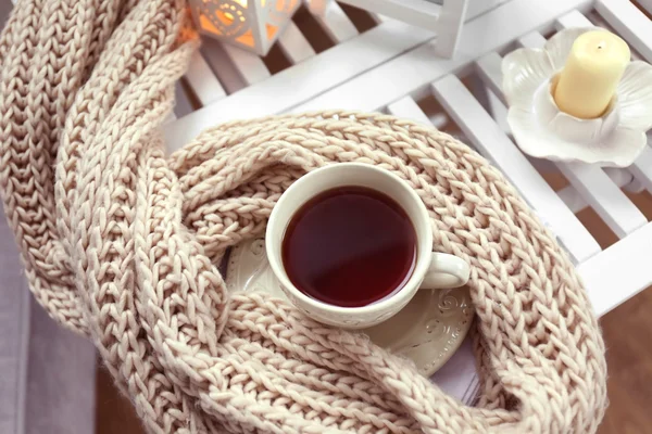 Tazza di tè e sciarpa in maglia sul tavolino in camera, da vicino — Foto Stock