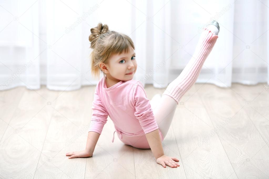 Little cute girl in pink leotard making new ballet movement at dance studio