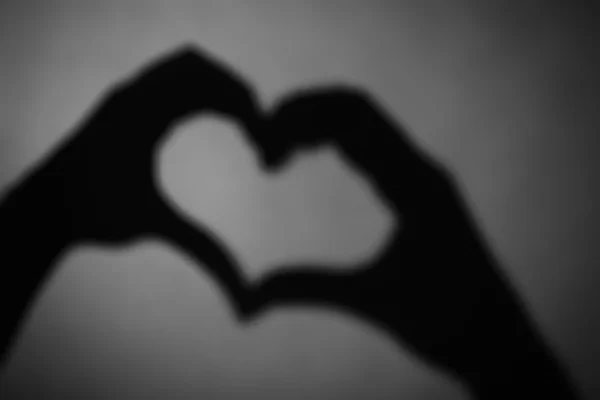 Mãos em forma de coração no escuro — Fotografia de Stock