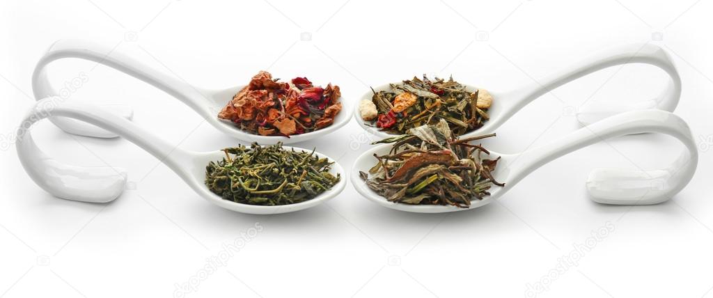 Different sorts of dry tea in ceramic spoons, isolated on white