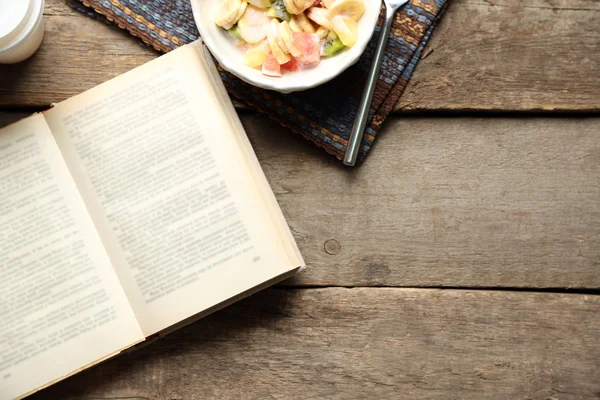 Open boek en snack op houten tafel achtergrond — Stockfoto