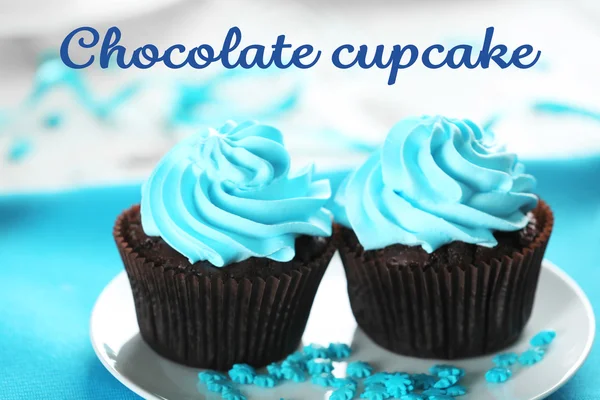 Вкусные шоколадные кексы с синим кремом на украшенном деревянном столе, крупным планом — стоковое фото