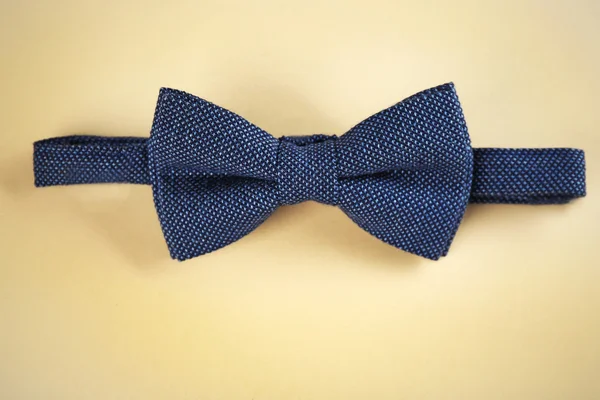 Dark blue bow tie on beige background — Stock Photo, Image