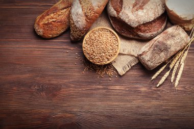 Taze pişmiş ekmek ve bir kase ahşap arka plan üzerinde buğday tanelerinin