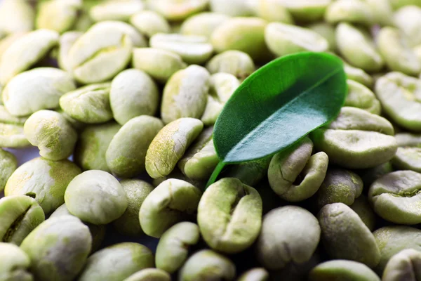 Haufen grüner Kaffeebohnen mit Blatt in Großaufnahme — Stockfoto