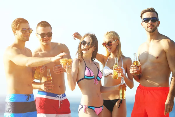 Счастливые друзья пьют пиво на пляже — стоковое фото