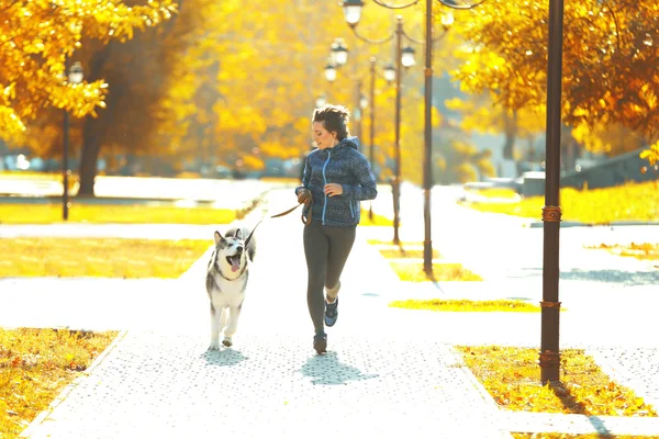 Mulher correndo com seu cão no parque — Fotografia de Stock