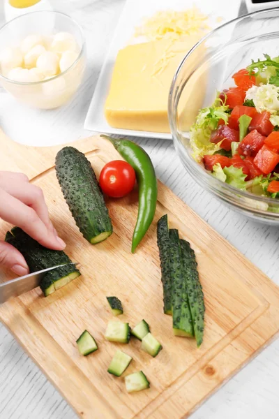 Vrouwelijke handen snijden groenten voor salade, in kitchen — Stockfoto