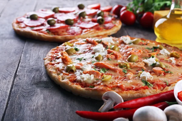 Heerlijke smakelijke pizza's met ingrediënten op tafel, close-up — Stockfoto