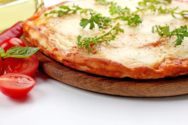 Pizza cheia de queijo em tábua de madeira com legumes isolados em fundo branco, close-up — Fotografia de Stock