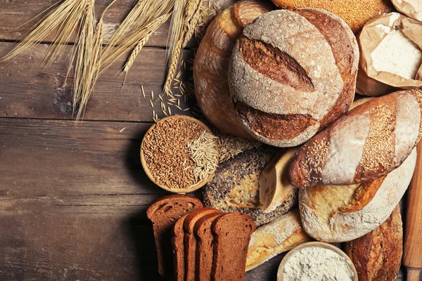 Pane appena sfornato, farina e grano sullo sfondo di legno — Foto Stock