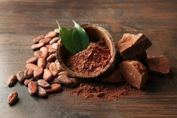 Bol avec poudre de cacao aromatique et feuille verte sur fond en bois, gros plan — Photo