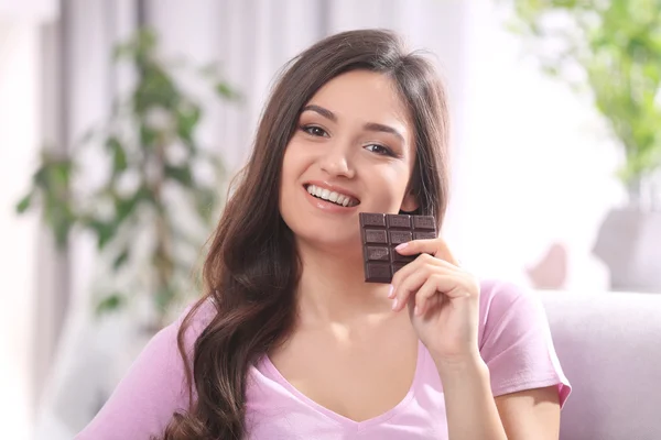 Portret piękne młoda brunetka z czekolady na kanapie w pokoju, z bliska — Zdjęcie stockowe