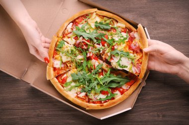 Elleriyle ahşap masa portre üzerinde dilimlenmiş pizza ile