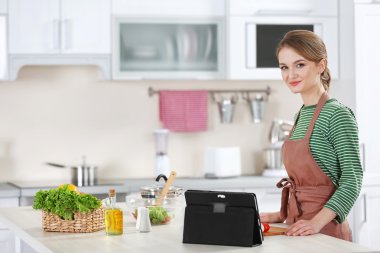 Genç bir kadın mutfakta yemek pişiriyor.