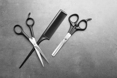 Tarak ve gri arka plan üzerinde iki makas Kuaför kümesiyle