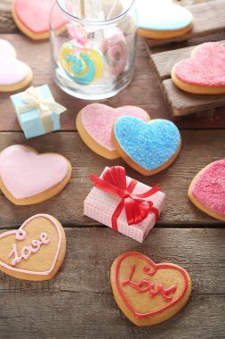 Mevcut kutuları ahşap arka plan üzerinde renkli Sevgililer kalp kurabiye