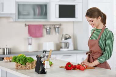 Genç bir kadın mutfakta yemek pişiriyor.