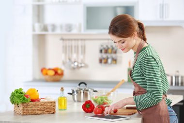 Genç bir kadın mutfakta yemek pişiriyor.