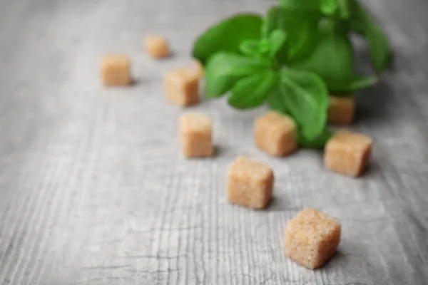 Montón de terrones de azúcar moreno y stevia sobre fondo de madera gris — Foto de Stock