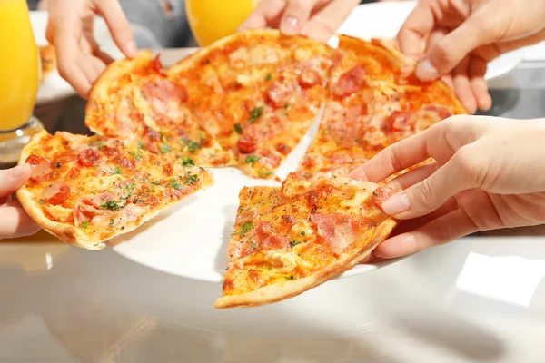Amici mani che tengono la pizza calda, da vicino — Foto Stock